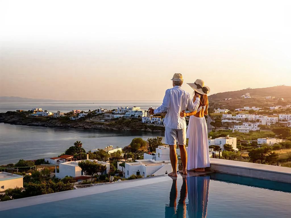 Couple enjoying a sunset view over a Mediterranean coastal village by the infinity pool